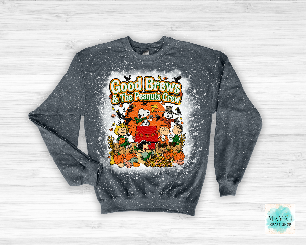 A heather charcoal crewneck sweatshirt featuring a 'Good Brews' graphic print on the front, laid flat on a white wood background.