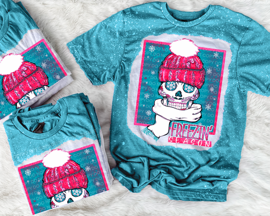 Galapagos t-shirt with a colorful graphic design featuring a skull wearing a pink hat and scarf, on a white textured background.