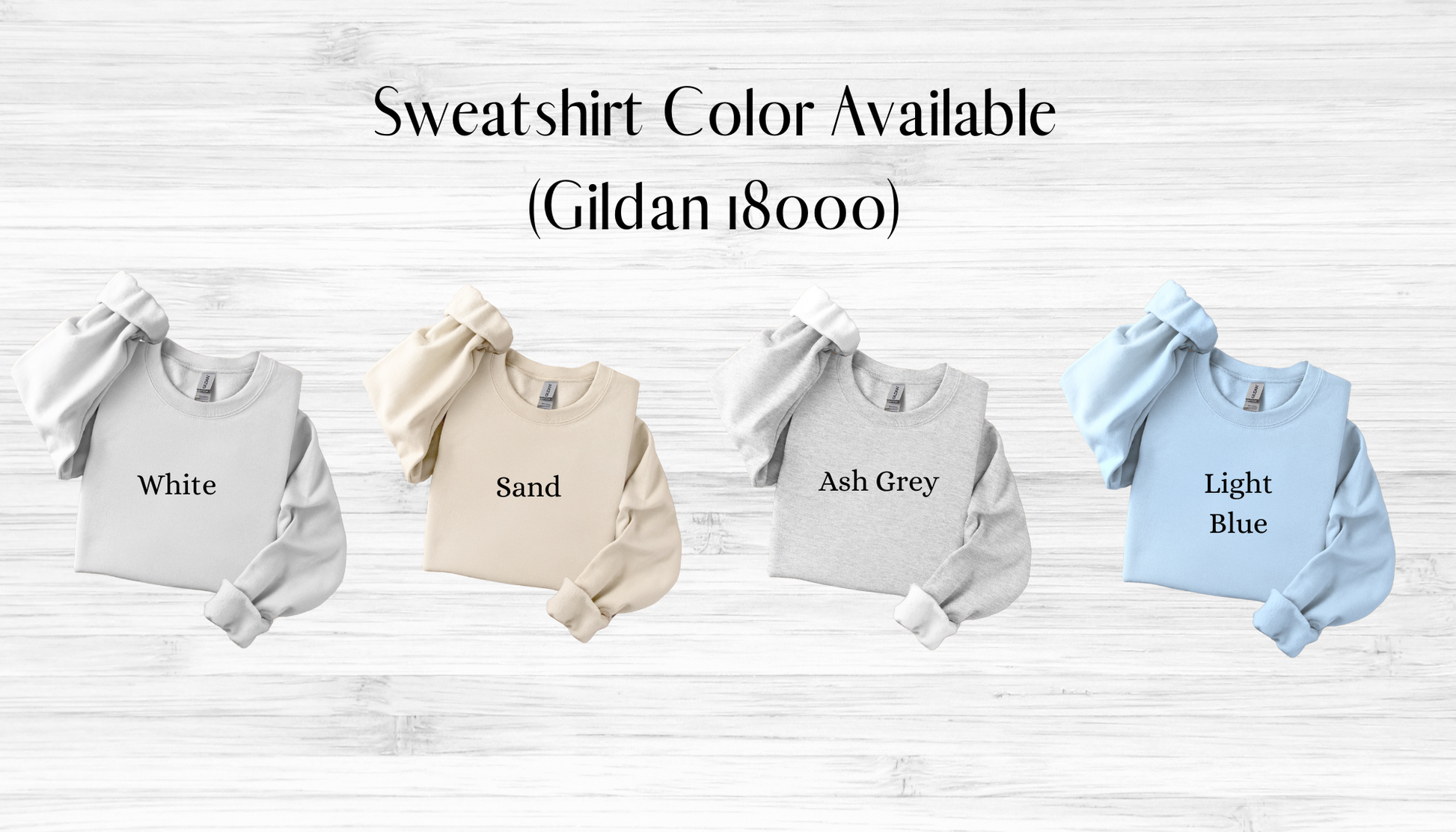 Four sweatshirts in white, sand, ash grey, and light blue on a wooden surface with text indicating color options.