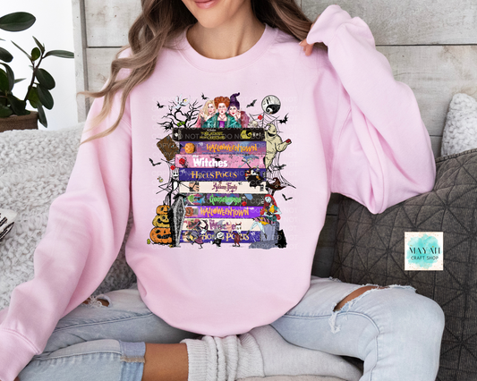 Person wearing a pink sweatshirt with Halloween movies book stack design, sitting on a couch.