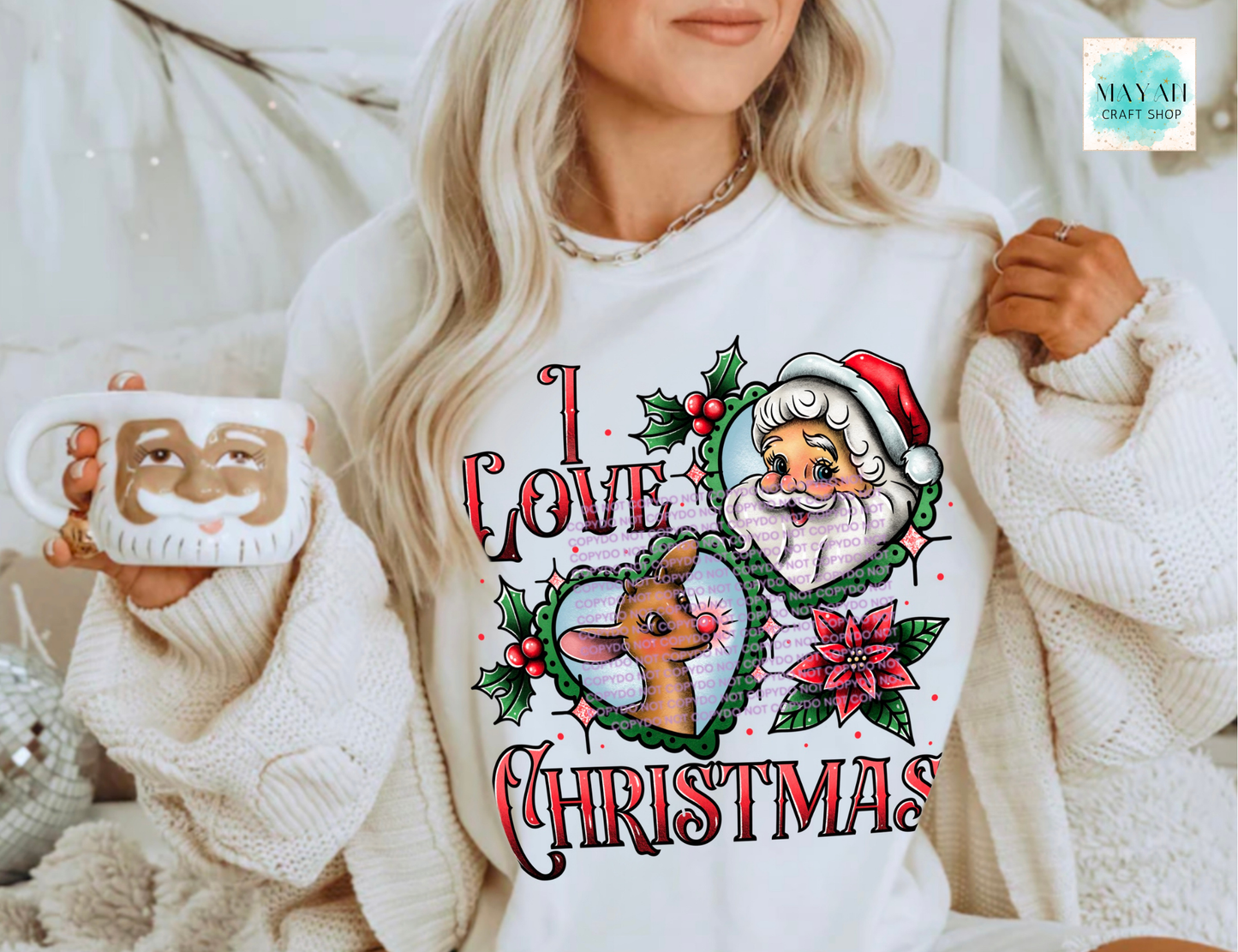 Person wearing a white sweater with Christmas-themed design, holding a mug.