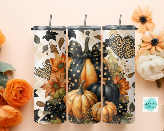 Three tumblers with autumn-themed designs featuring pumpkins and leaves on a beige background.