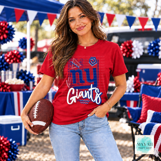 A woman wearing a red football team graphic t-shirt and light blue jeans, holding a brown football in an outdoor patriotic tailgate setting decorated with red, white, and blue balloons and banners.