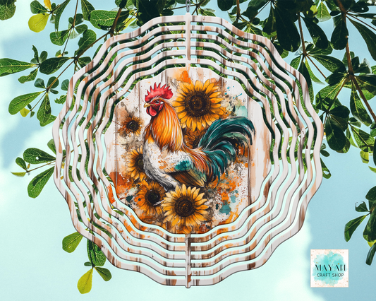 Decorative wind spinner with a rooster and sunflowers design, surrounded by green leaves.