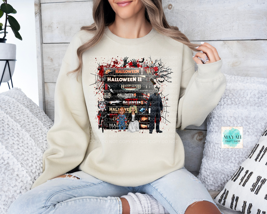 Person wearing a cream sweatshirt with scary movies design, sitting on a white couch.