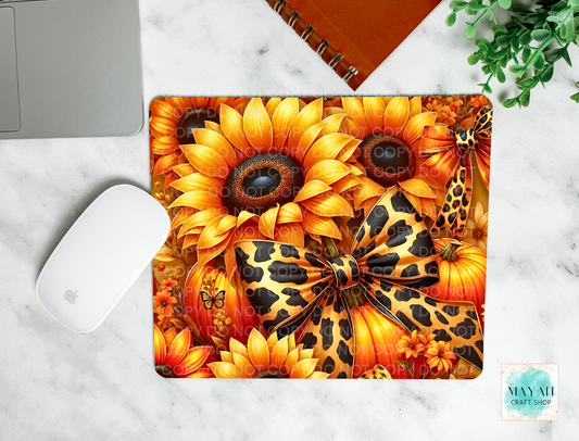 Decorative mouse pad with sunflower and leopard print design on a marble surface.