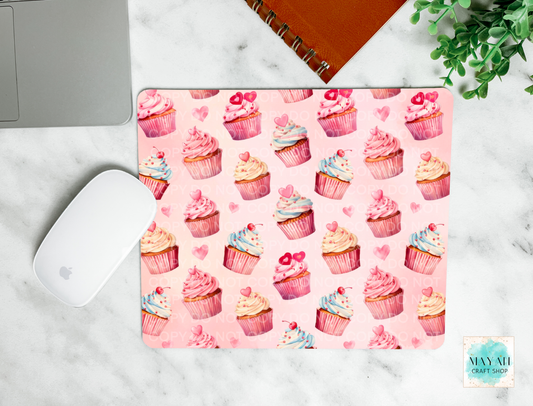 Pink mouse pad with cupcake pattern on a marble surface