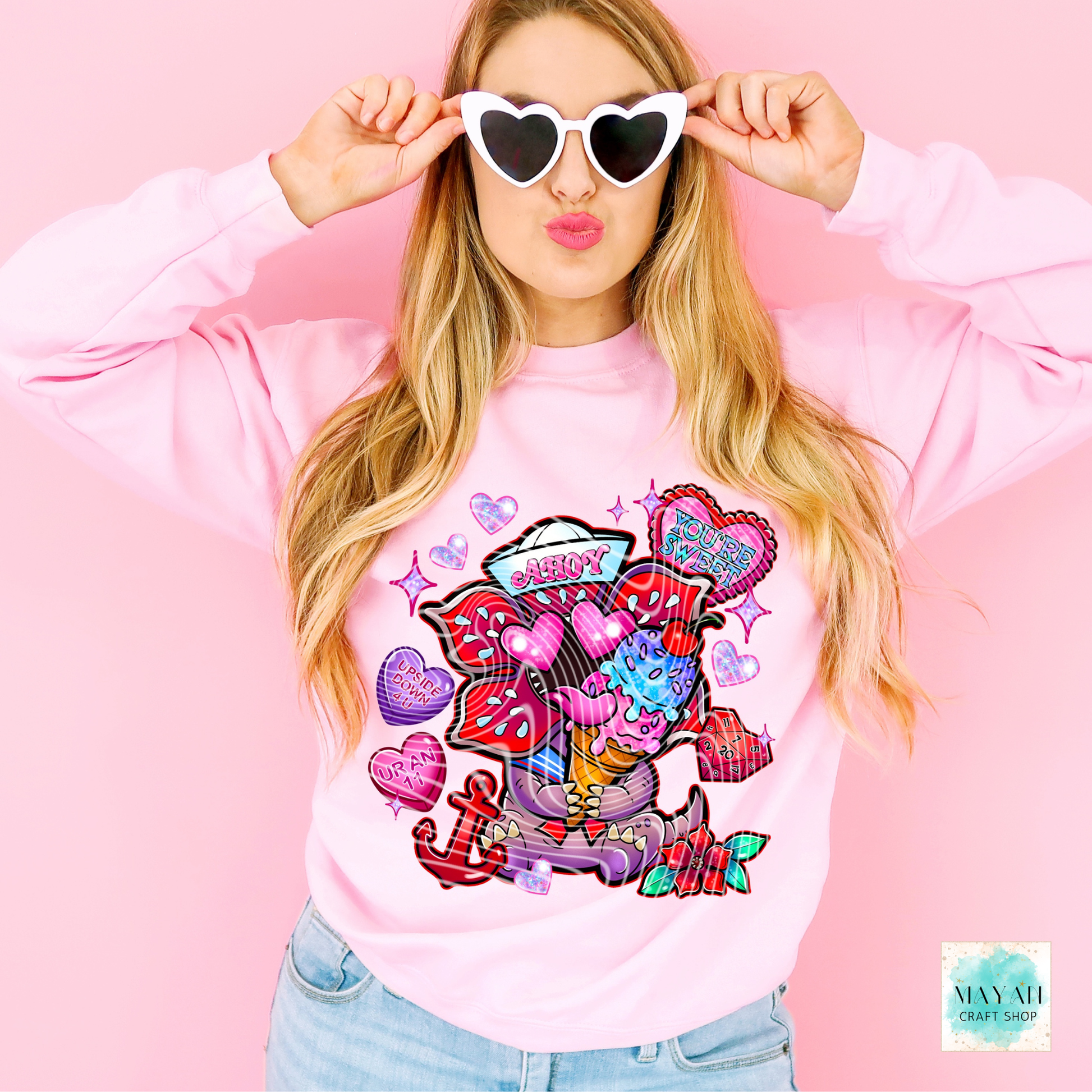 Woman wearing a pink sweatshirt with colorful graphics and text on a pink background