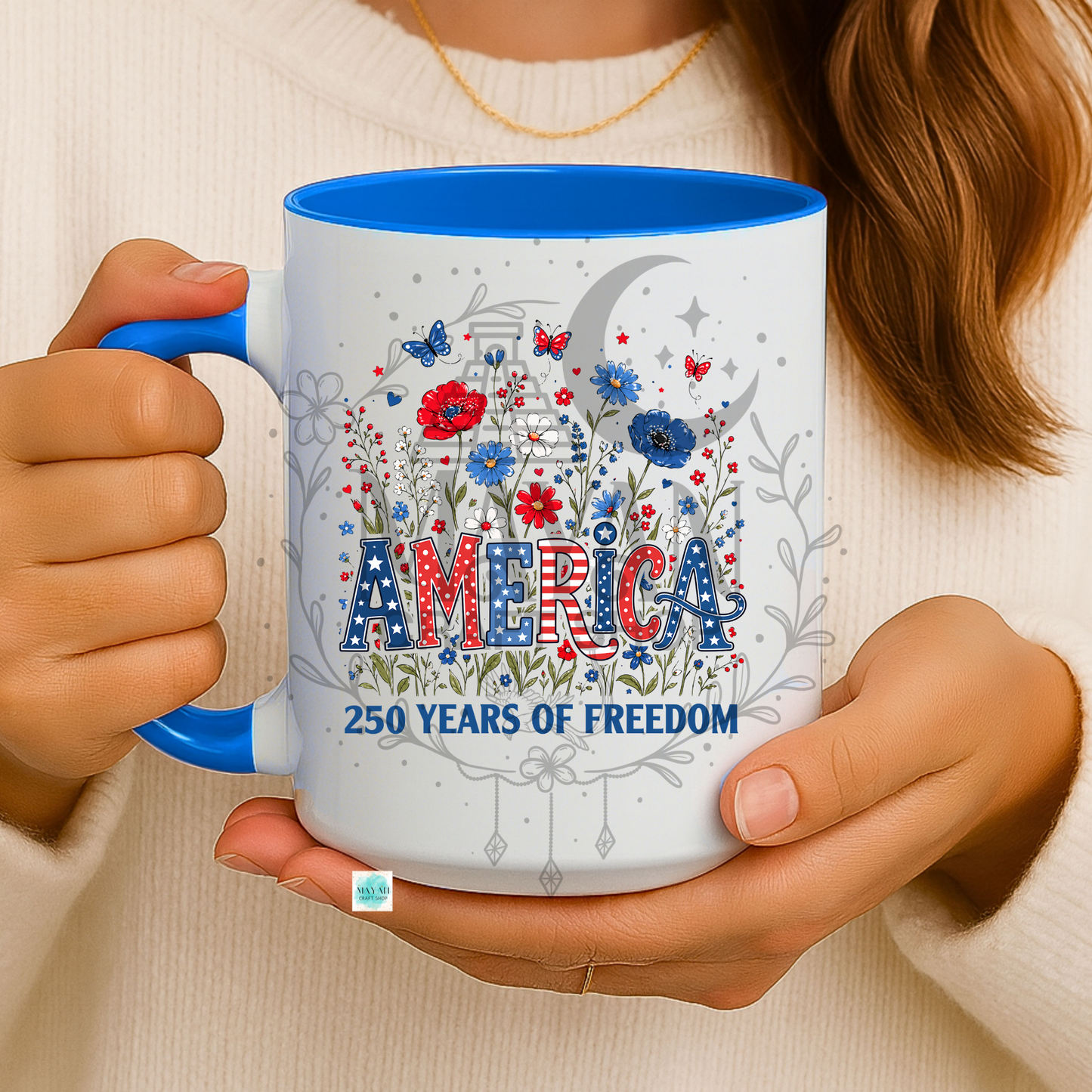 Person holding a mug with 'America 250 Years of Freedom' design featuring flowers and stars.