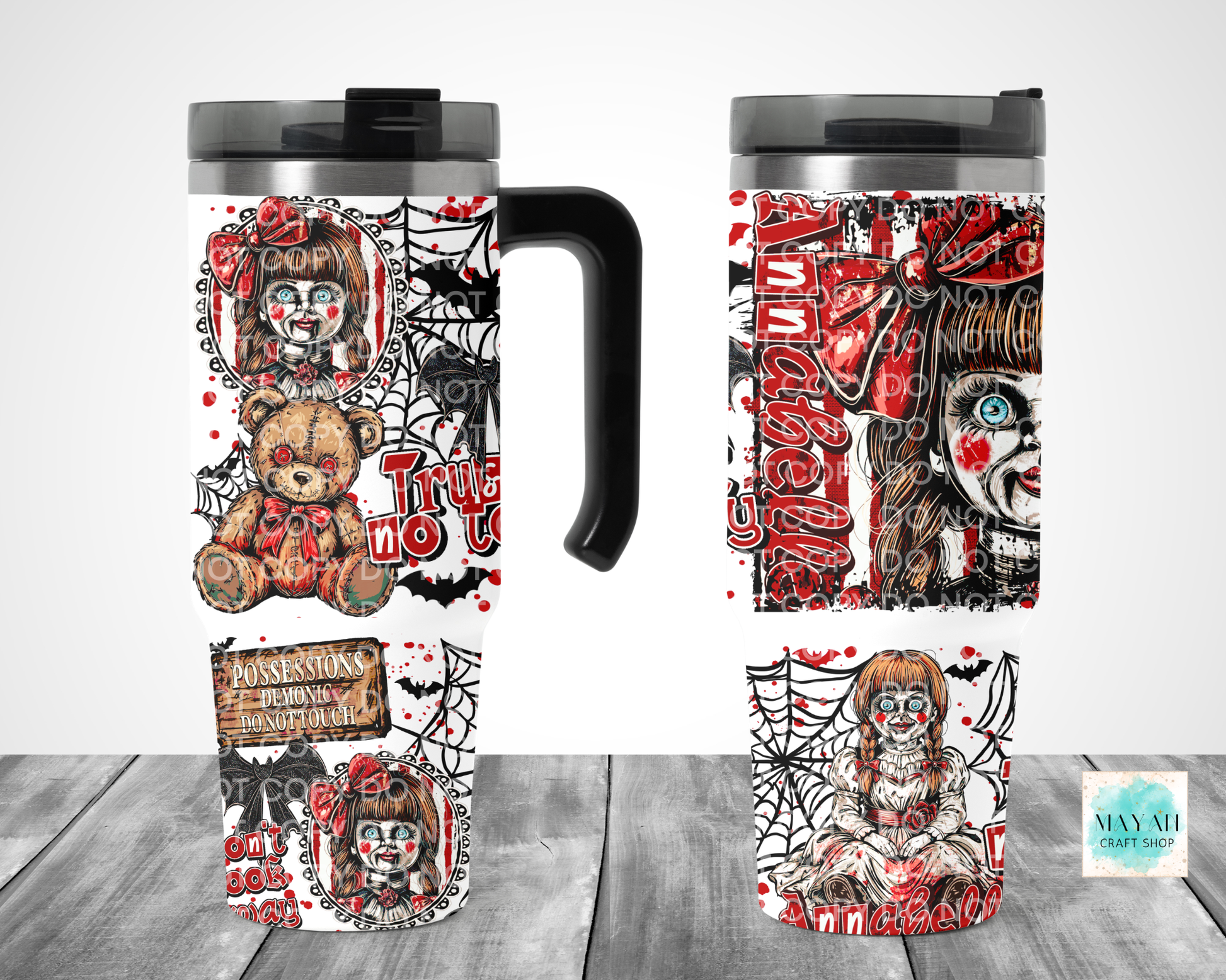 A Halloween-themed travel tumbler mug shown from multiple angles on a gray wood surface against a white background. The mug features a black handle and lid, with a wraparound design in red, black, and white showing a creepy clown doll, spiderwebs, bats.