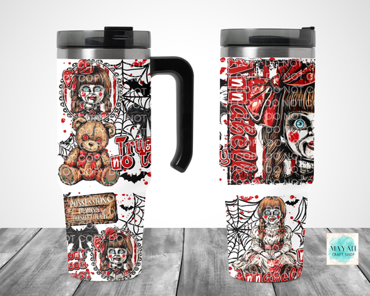 A Halloween-themed travel tumbler mug shown from multiple angles on a gray wood surface against a white background. The mug features a black handle and lid, with a wraparound design in red, black, and white showing a creepy clown doll, spiderwebs, bats.