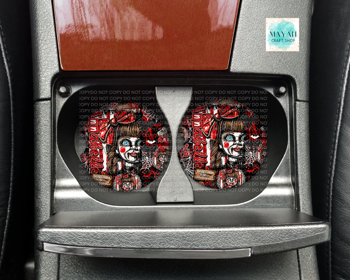 A pair of circular car cup holders installed in a center console, featuring a horror-themed graphic of a creepy clown character with red and black colors. The image is taken inside a car.