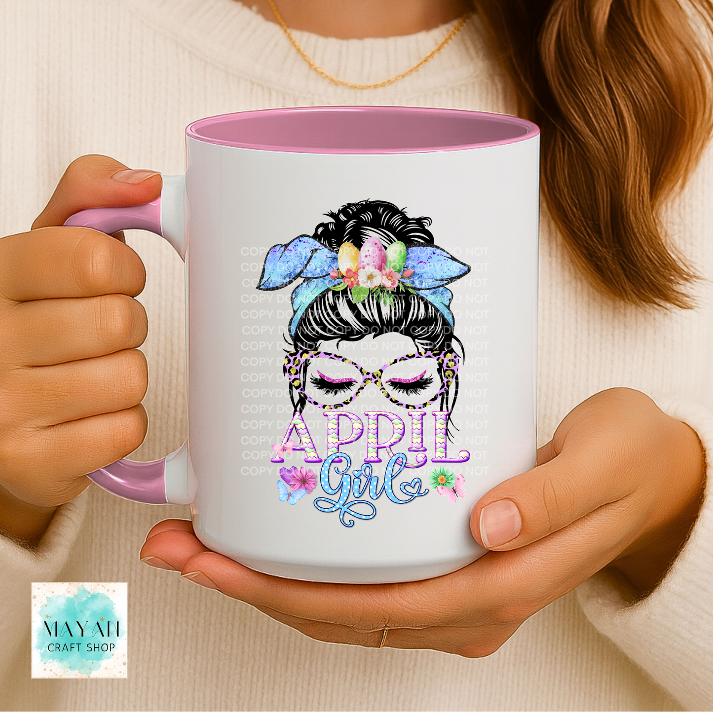 Person holding a mug with a colorful design and text, featuring a brand logo in the corner.