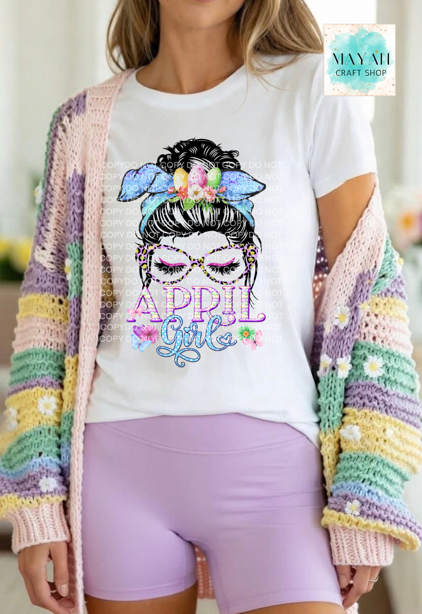 Person wearing a white t-shirt with a colorful graphic design and a multicolored cardigan.