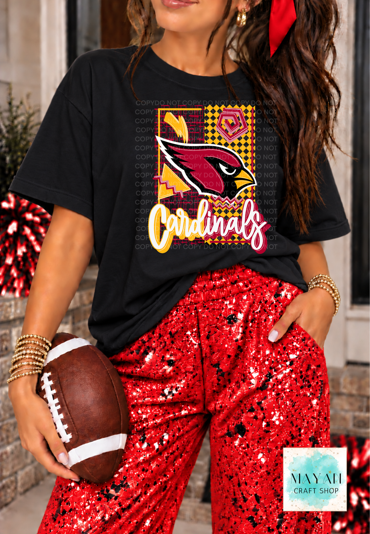 A woman wearing a black graphic T-shirt with a football team design and red sequined pants, holding a football. The photo is cropped from the lower face to the upper thighs.