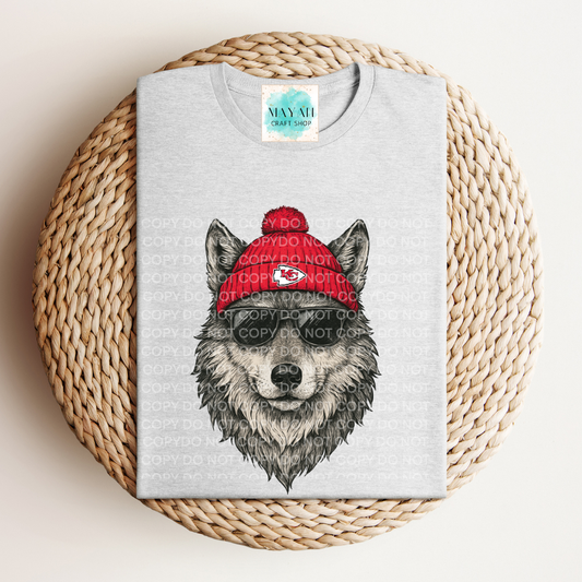 Gray t-shirt with a wolf graphic wearing a red beanie on a woven surface