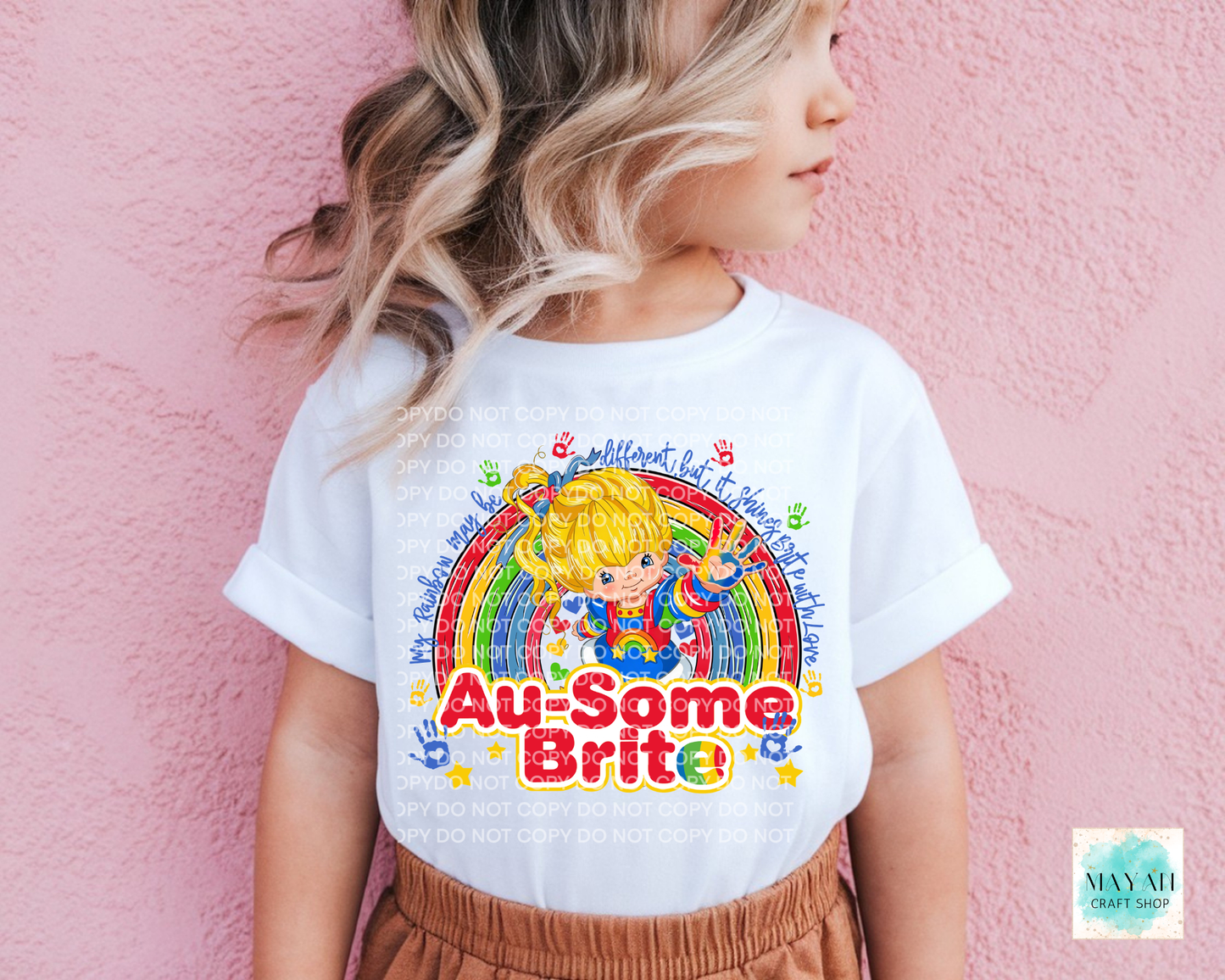 Child wearing a white t-shirt with colorful graphics and text against a pink background