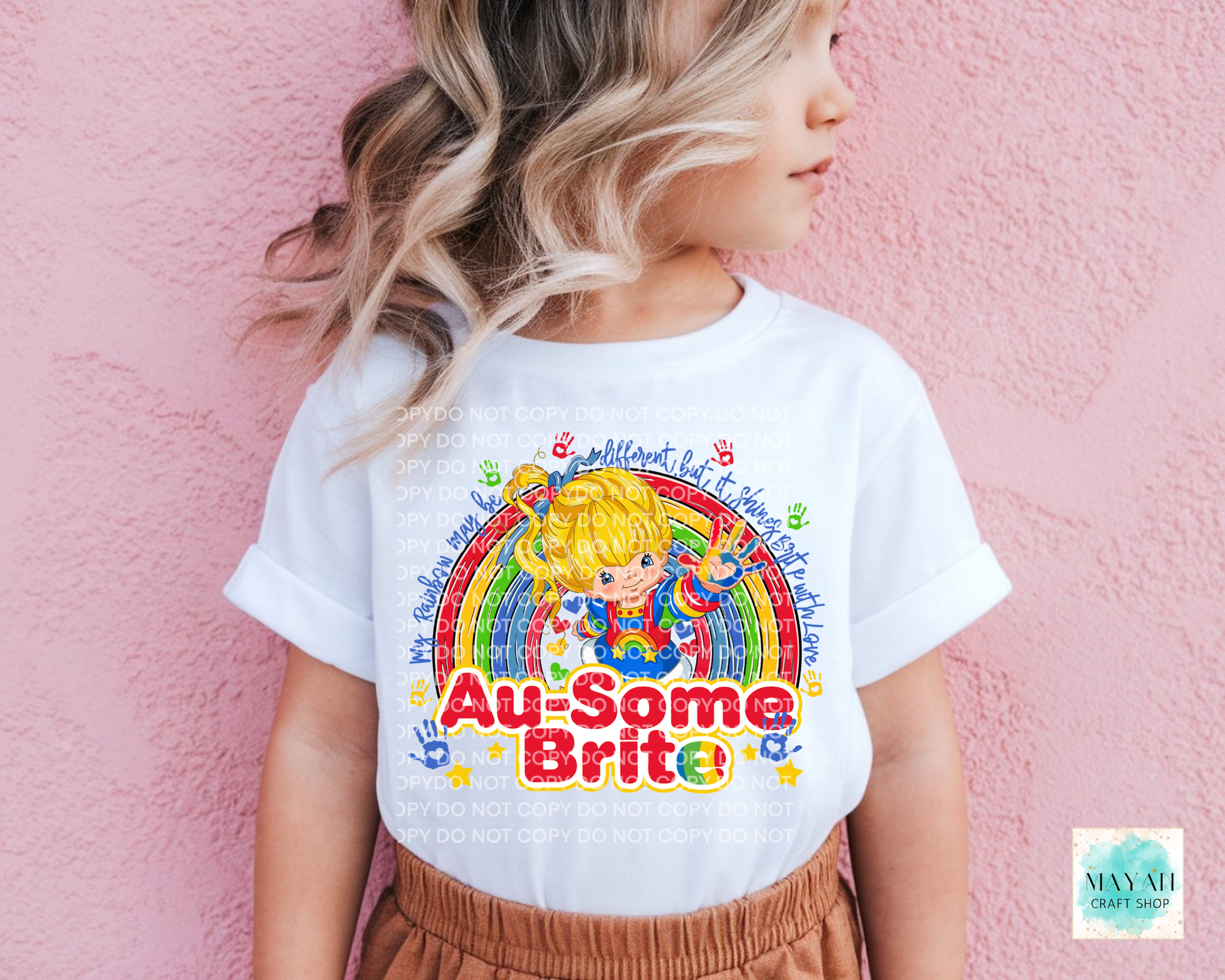 Child wearing a white t-shirt with colorful graphics and text against a pink background