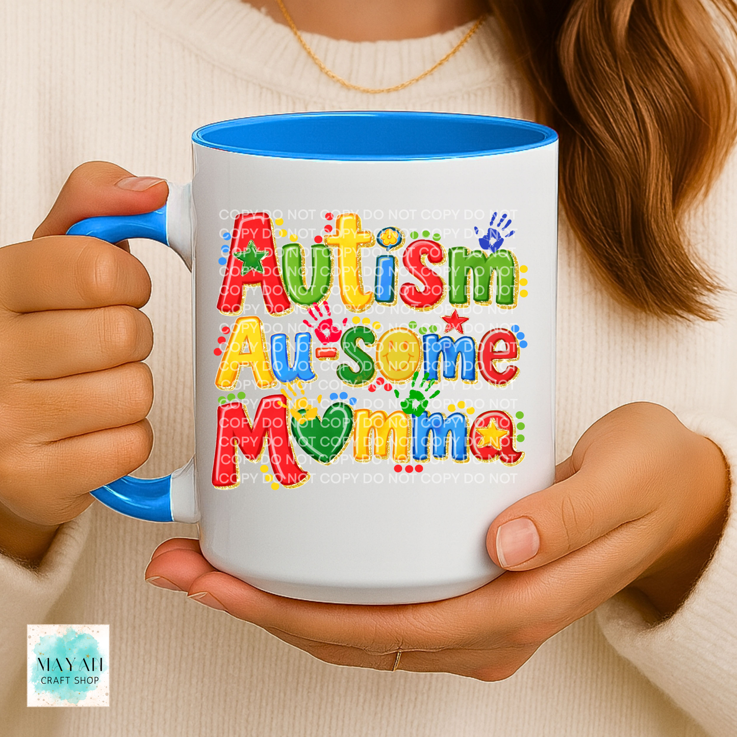 Person holding a mug with 'Autism Au-some Mama' text in colorful letters.