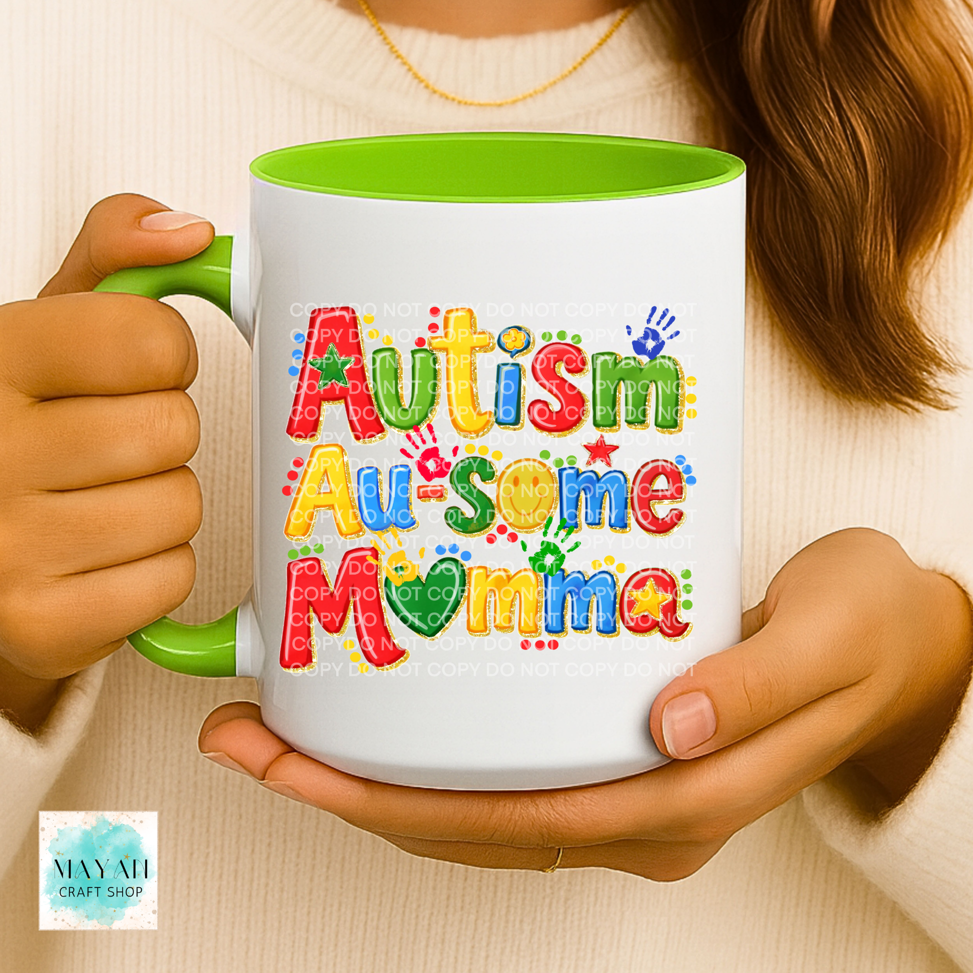 Person holding a mug with 'Autism Au-some Mamma' text and colorful design.