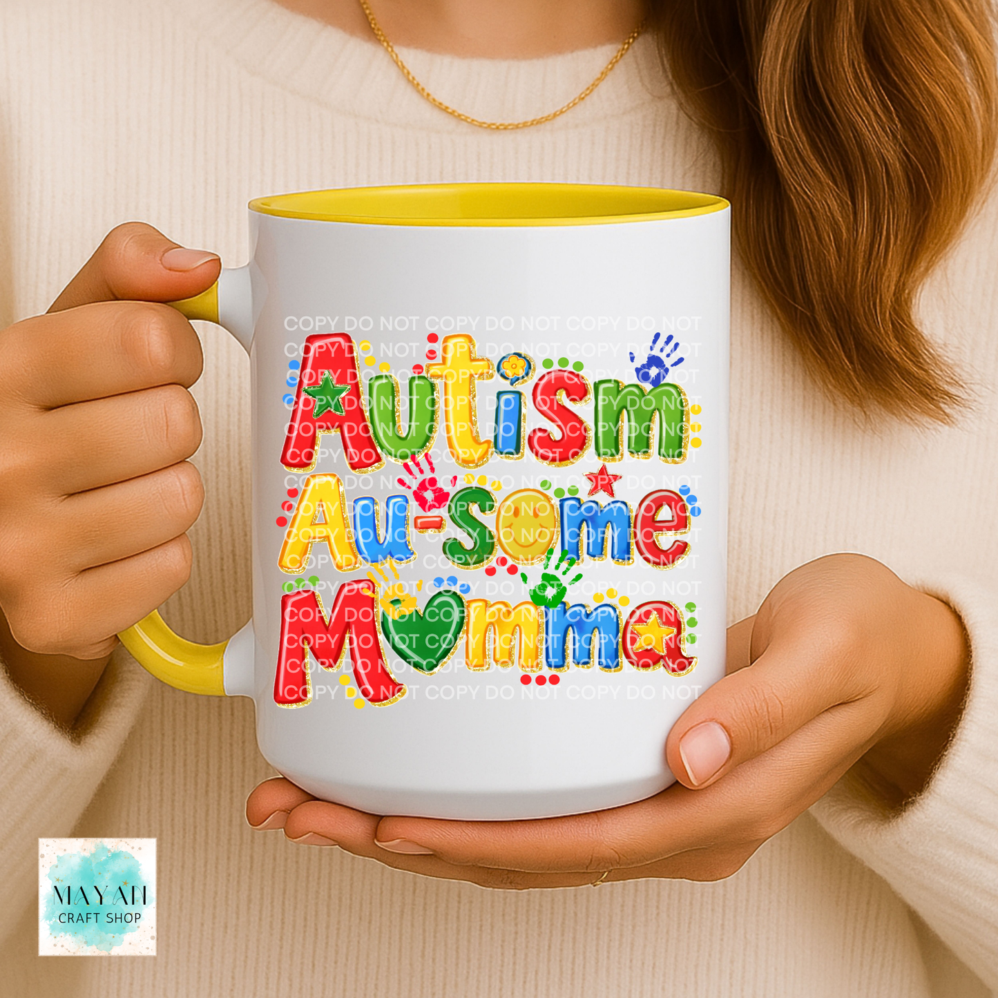 Person holding a mug with 'Autism Au-some Momma' text in colorful letters.