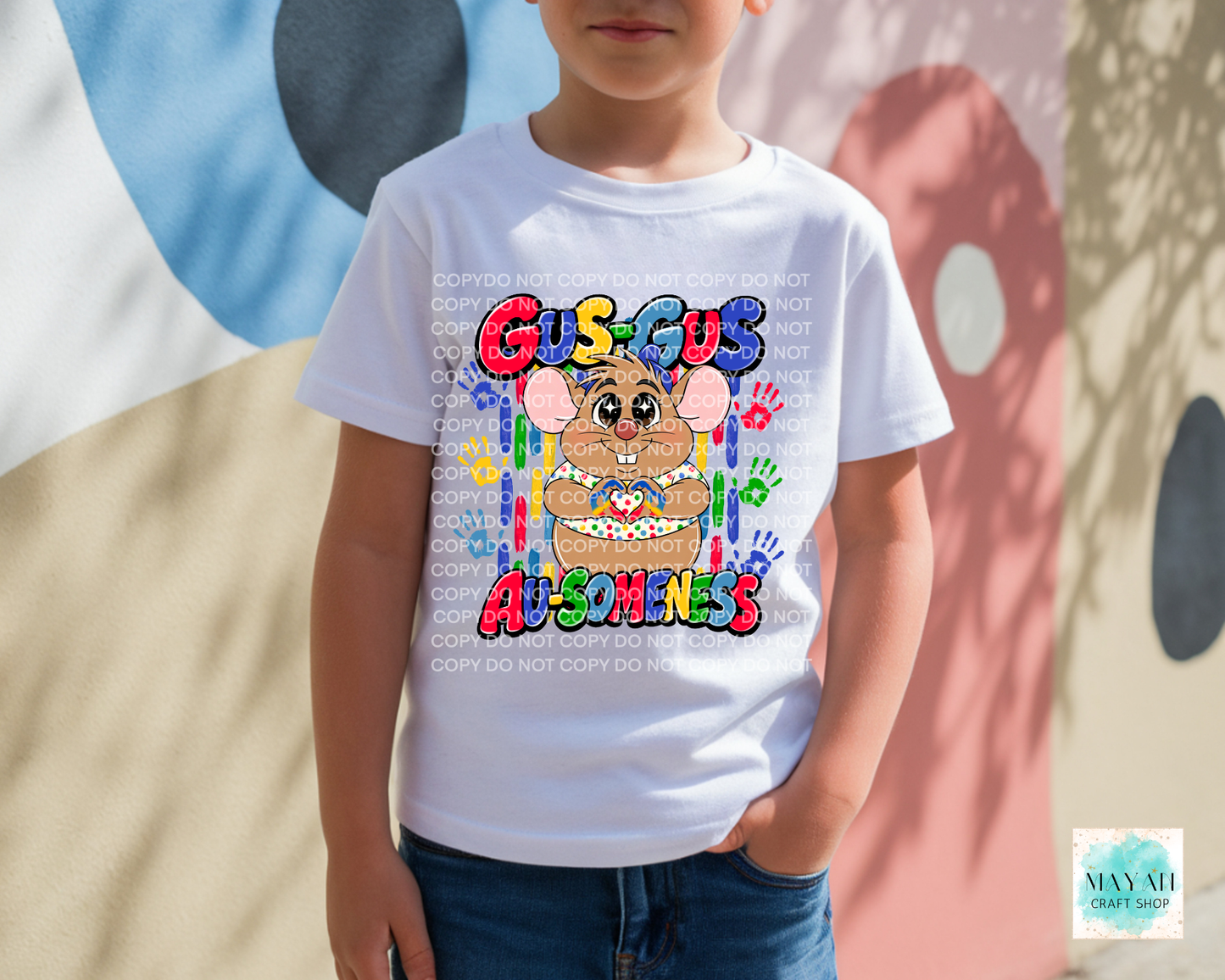 Child wearing a white t-shirt with colorful graphics and text, standing against a multicolored background.