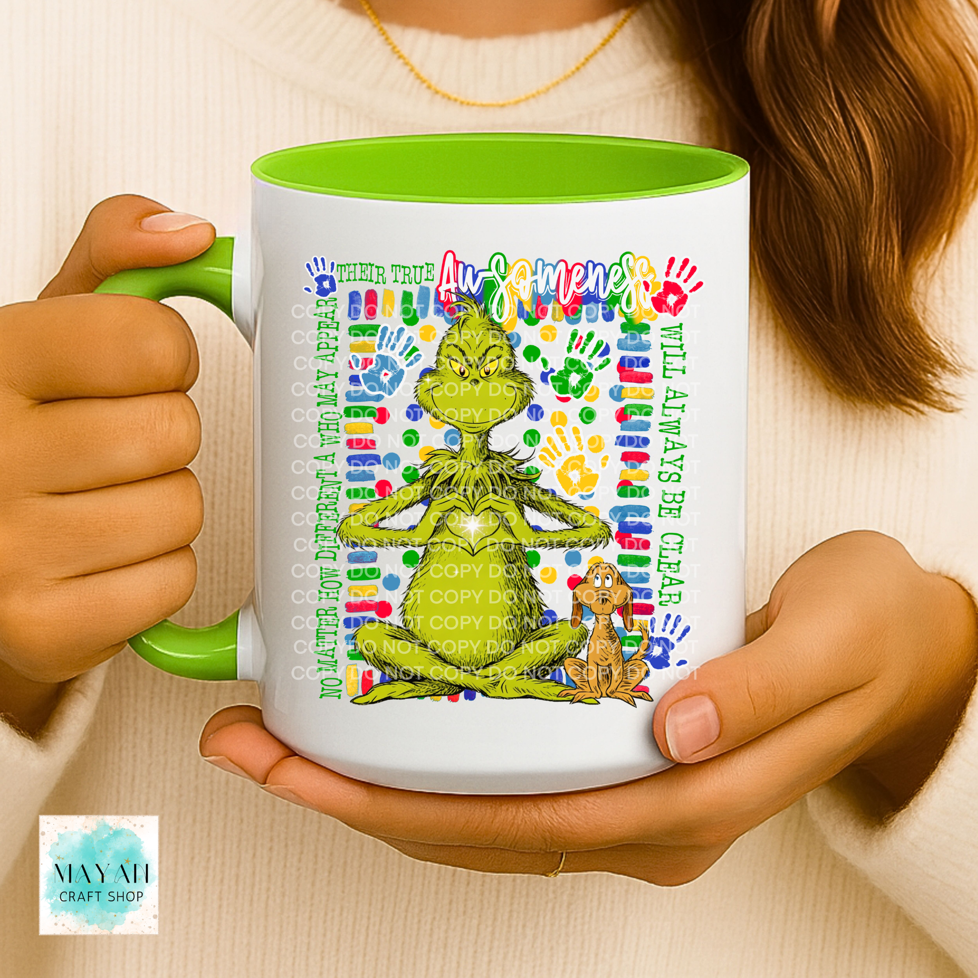 Person holding a mug with a colorful design featuring a green character and text.