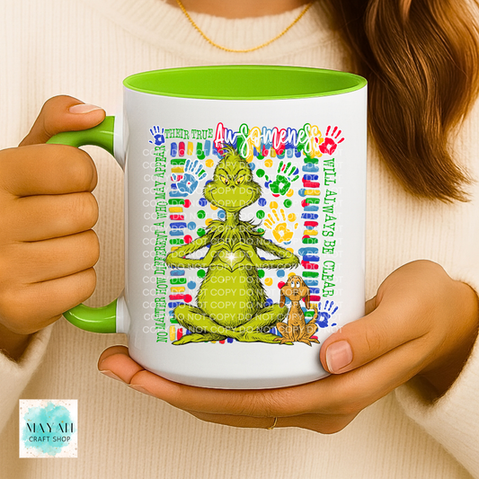 Person holding a mug with a colorful design featuring a green character and text.