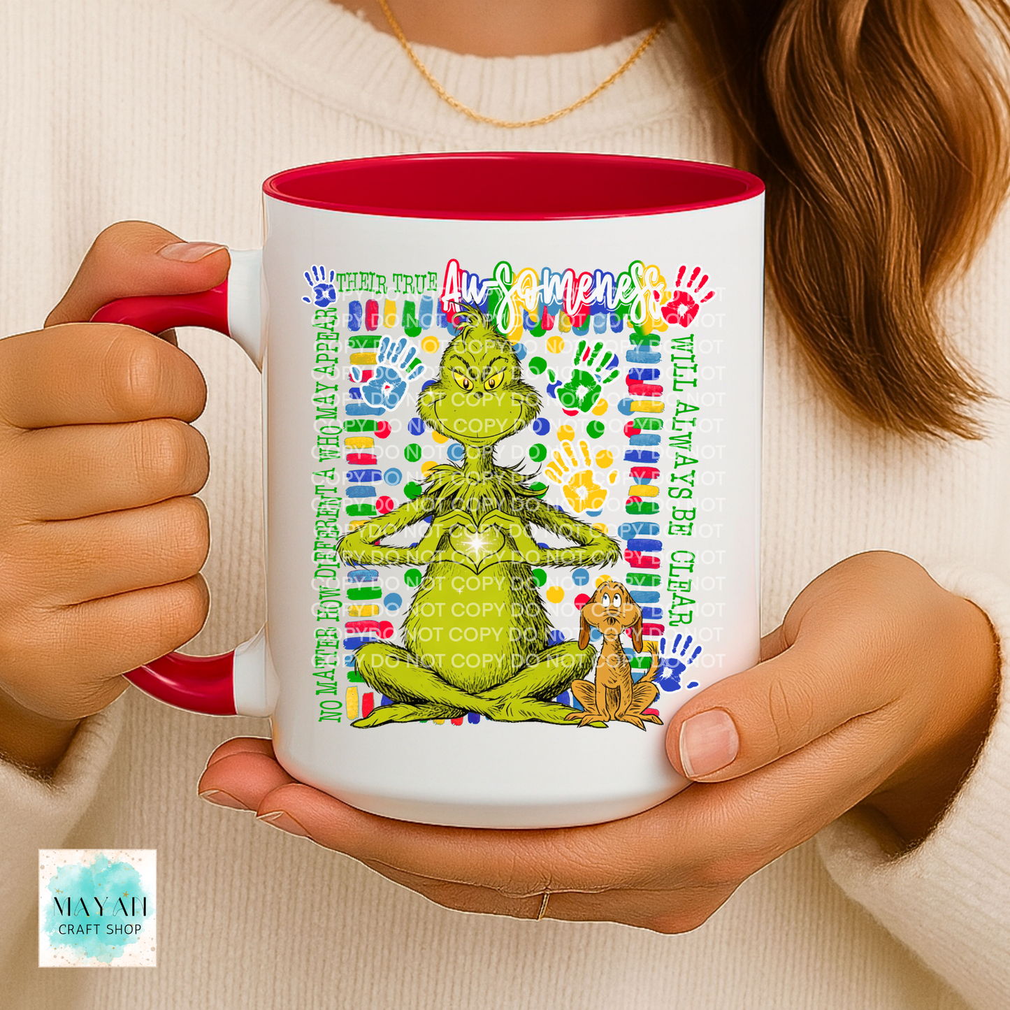 Person holding a mug with a colorful design featuring a green character and text.