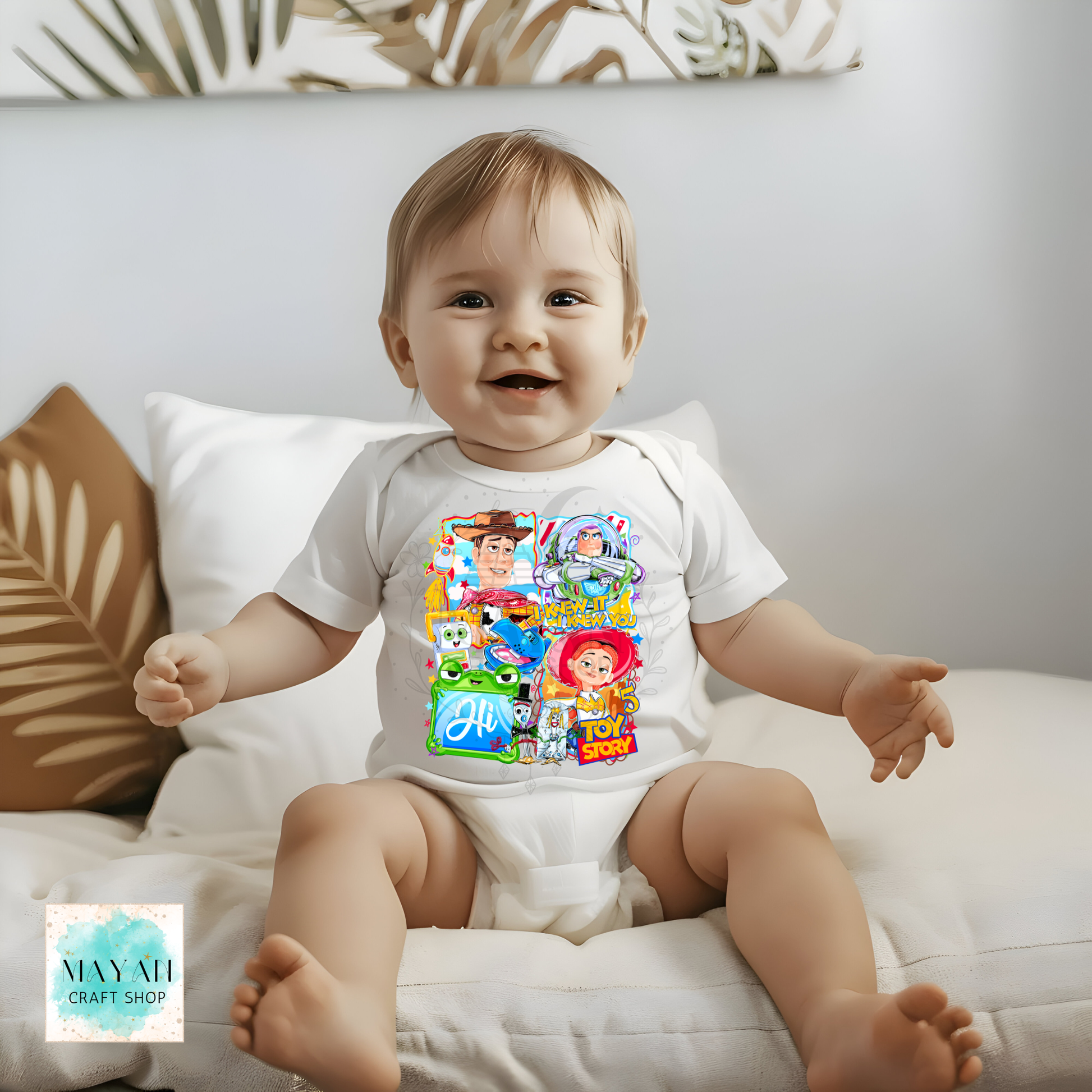 Baby wearing a colorful cartoon-themed onesie sitting on a couch.
