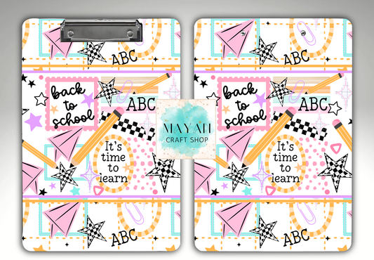 Two matching clipboards with a colorful 'Back to School' pattern, featuring pink paper airplanes, yellow pencils, checkered stars, and the text 'back to school', 'It's time to learn', and 'ABC'. 
