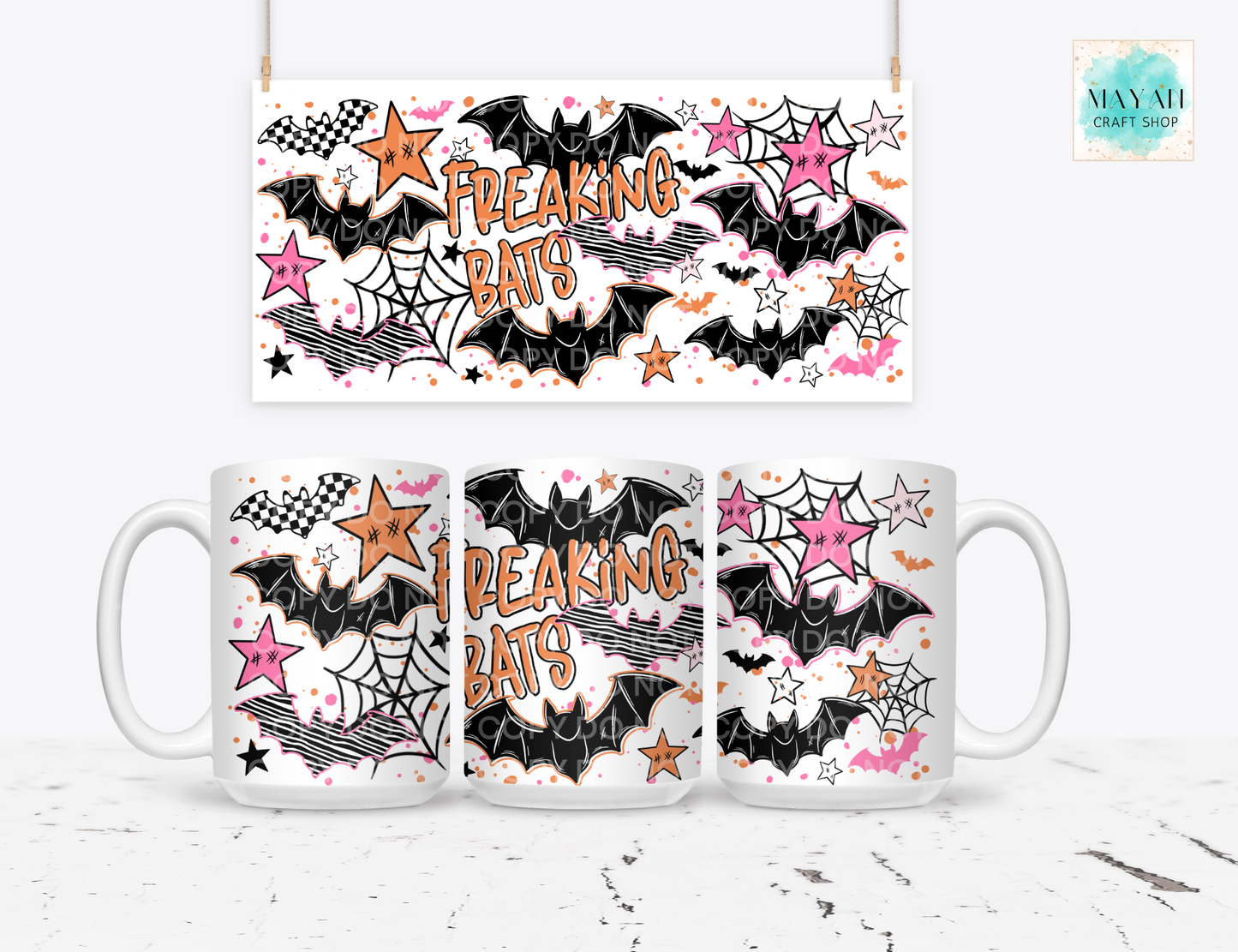 A white ceramic mug shown from three angles with a matching hanging banner above it, both printed with a Halloween-style design featuring black bats, pink and orange stars, spiderwebs, and the words “FREAKING BATS.”.
