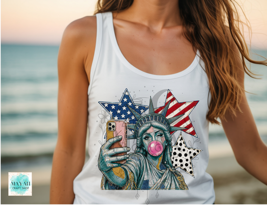 Person wearing a white tank top with a Statue of Liberty graphic at the beach