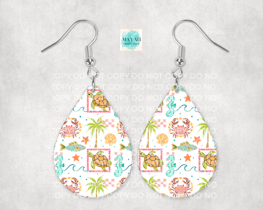 Teardrop-shaped earrings with a tropical pattern featuring turtles, palm trees, and crabs on a white background.