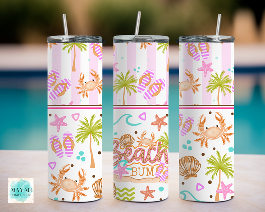 Three tumbler with beach-themed designs on a blurred outdoor background