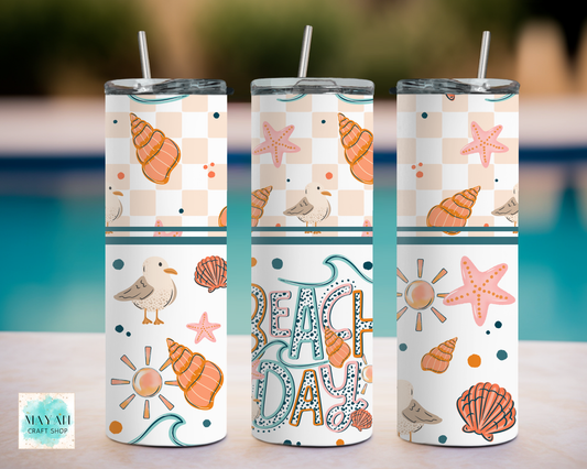 Three tumblers with beach-themed designs on a blurred background