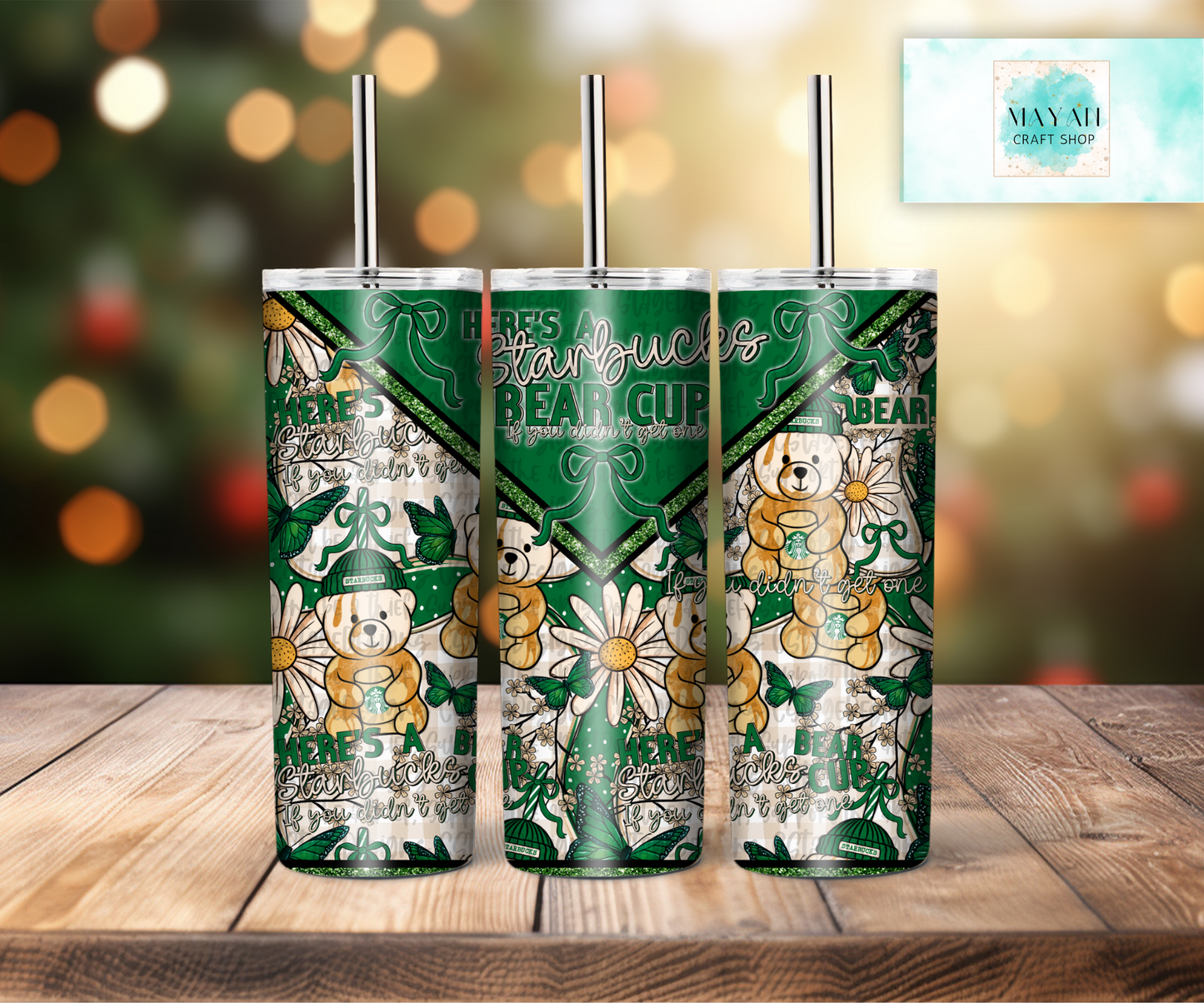 Three green tumblers with teddy bear designs on a wooden surface with a blurred background.