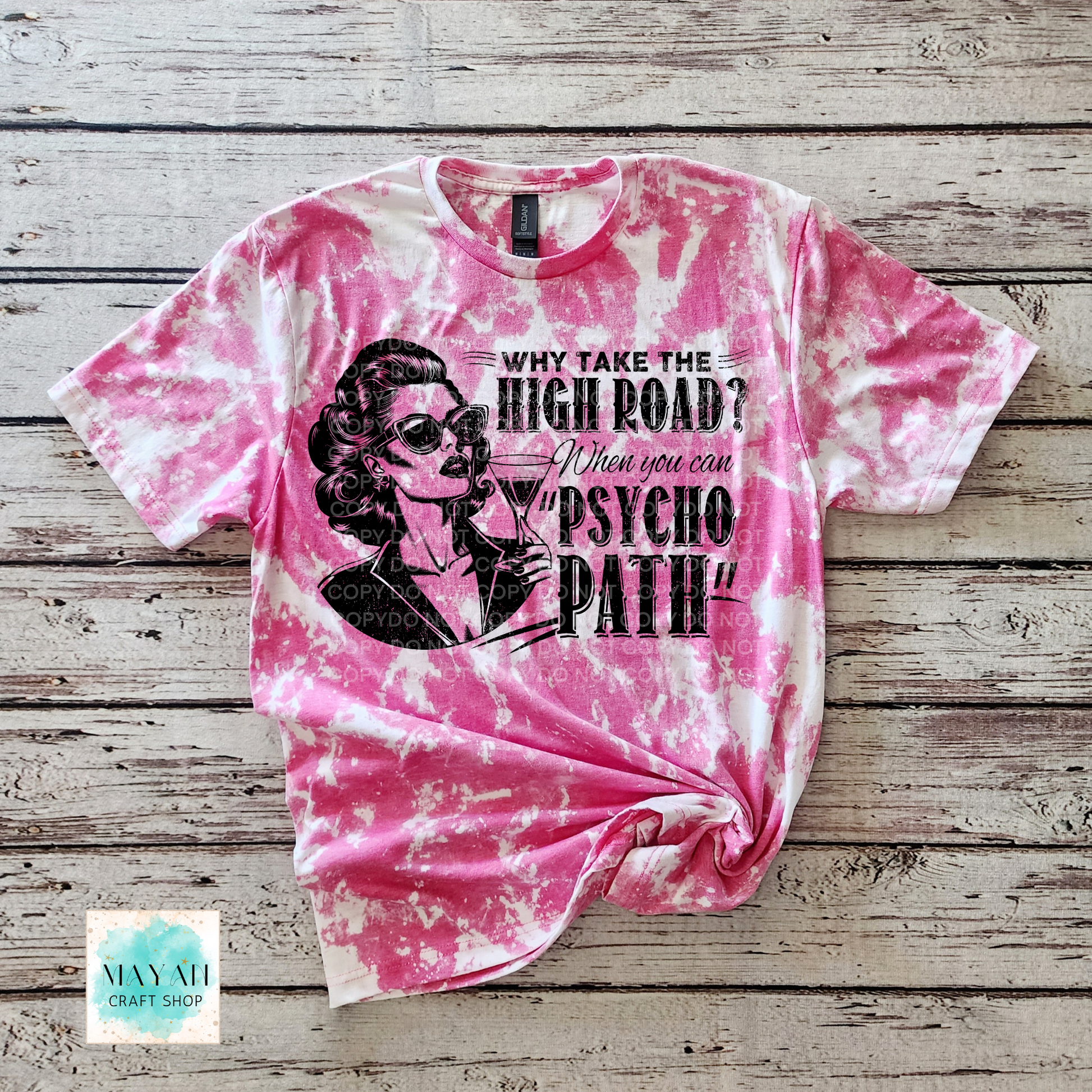 Pink tie-dye t-shirt with graphic design and text on a wooden surface