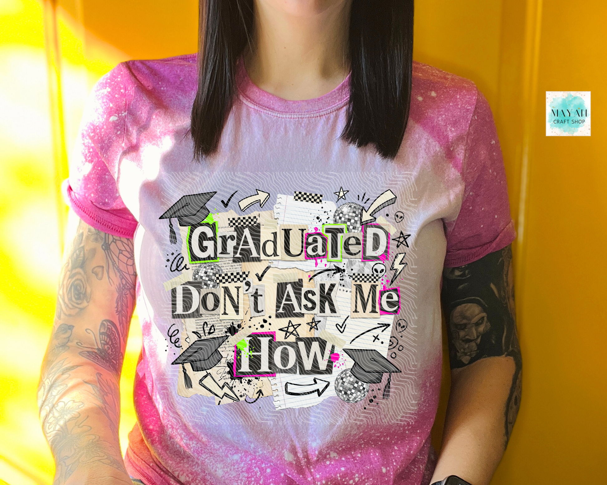 Person wearing a pink and white t-shirt with graduation-themed text against a yellow background