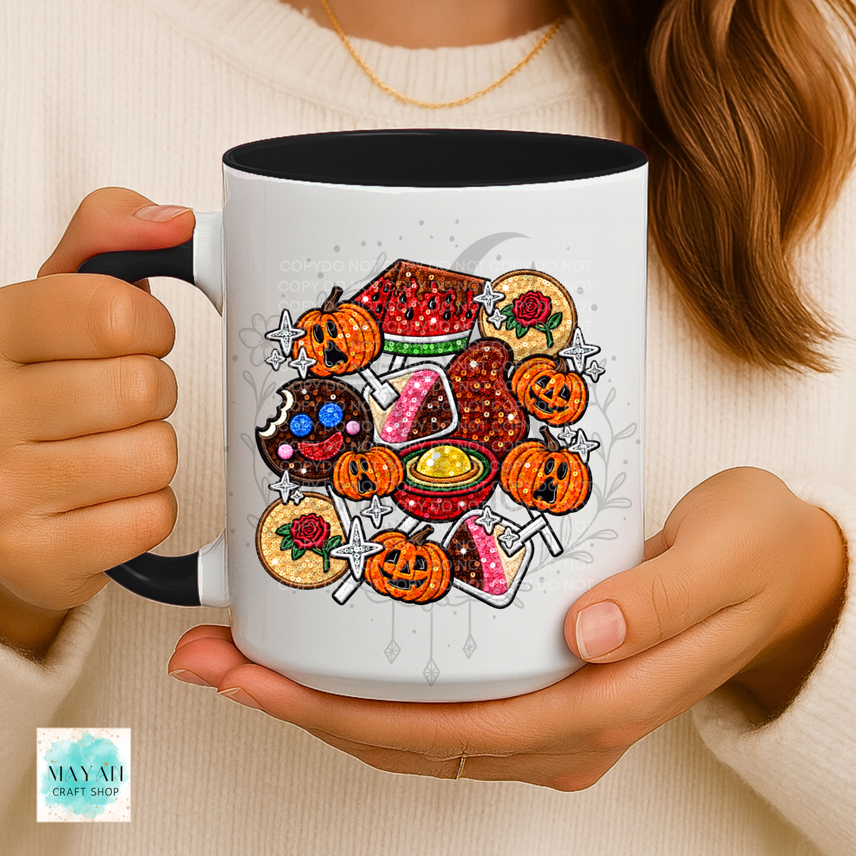 A person holds a white ceramic mug with a black handle and interior. The mug is decorated with a colorful Halloween-themed illustration featuring mexican candy.
