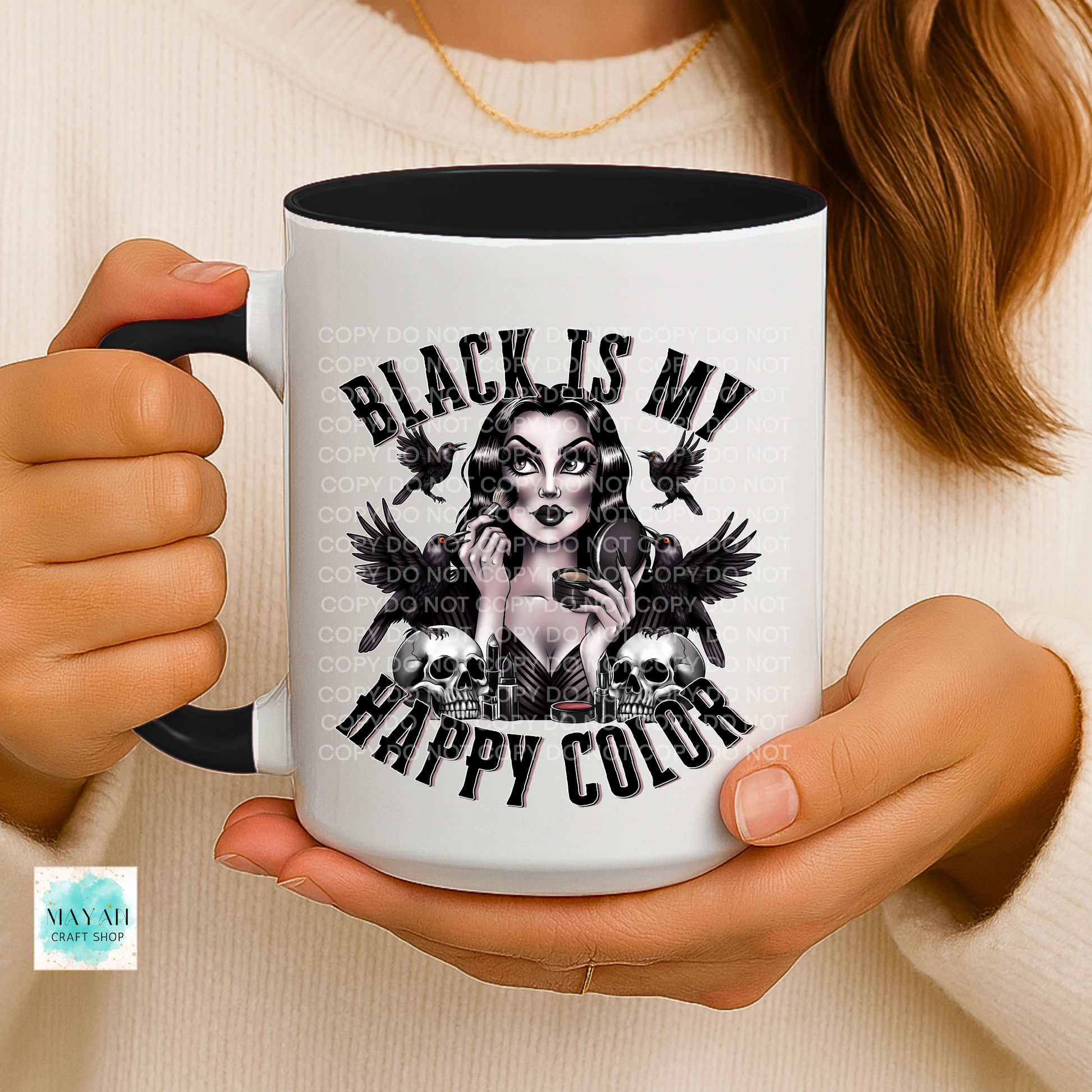 Person holding a mug with a graphic design and text, wearing a white sweater.