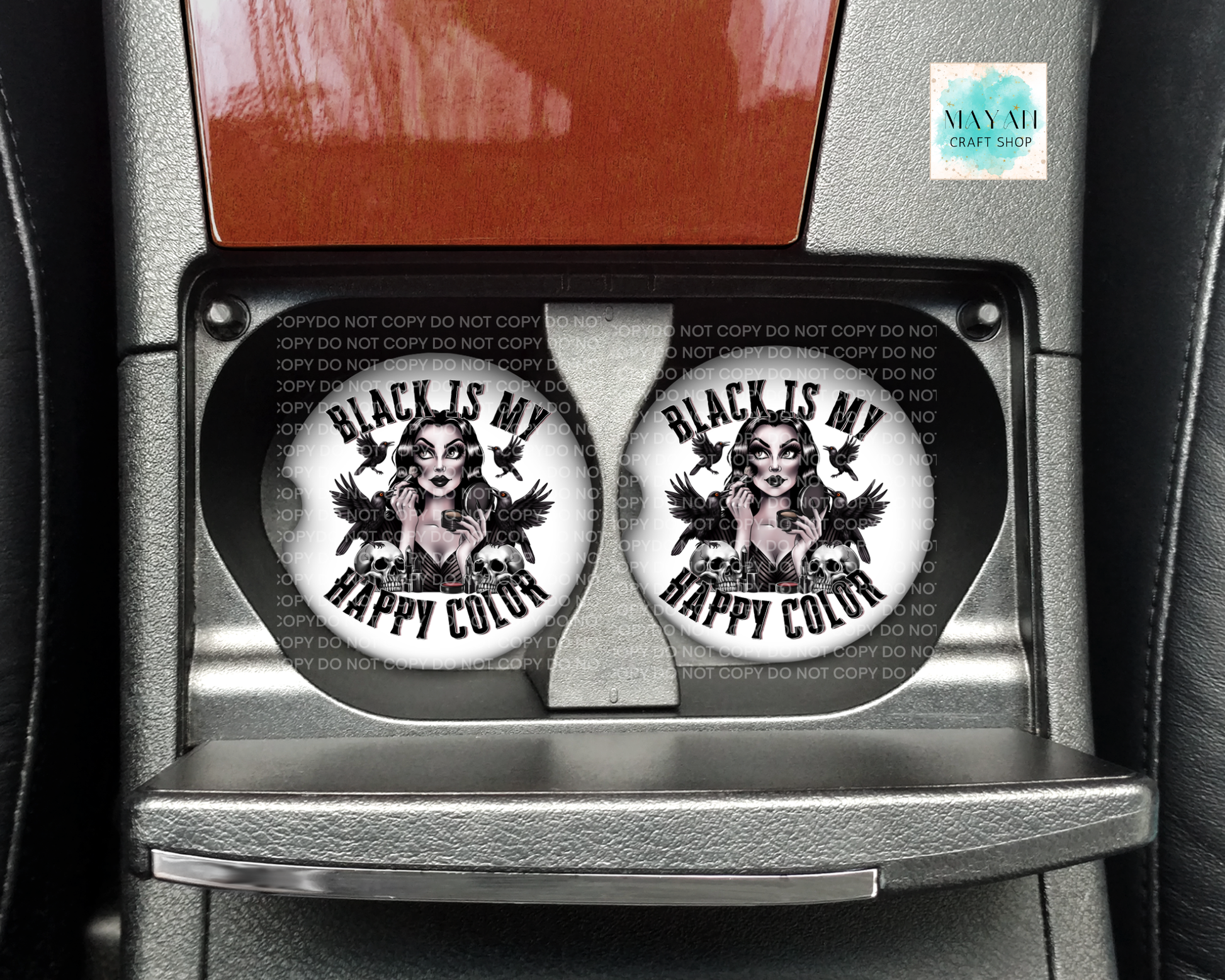 Two circular coasters with a design and text 'Black is my happy color' on a car dashboard.