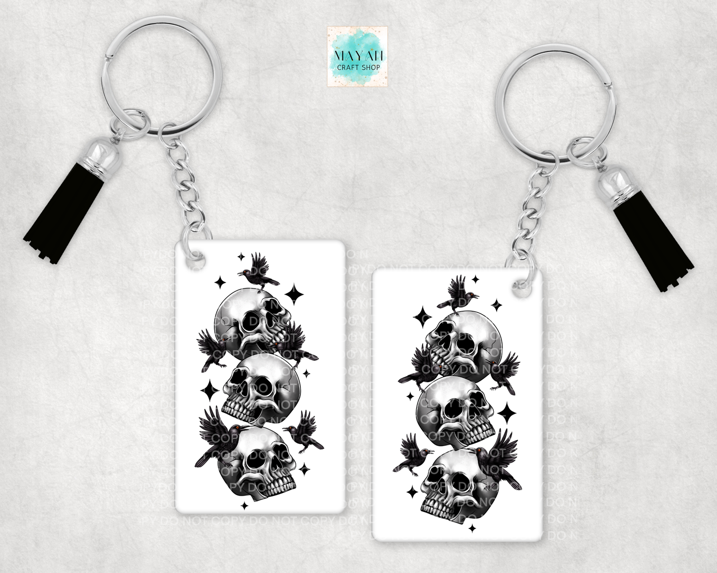Two keychains with skull and bird design on a light gray background