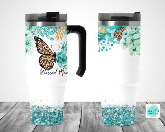 Two travel mugs with butterfly design and turquoise floral pattern on a wooden surface.