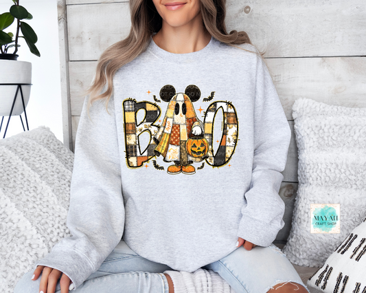 Person wearing a light gray sweatshirt with Halloween-themed design sitting on a couch.