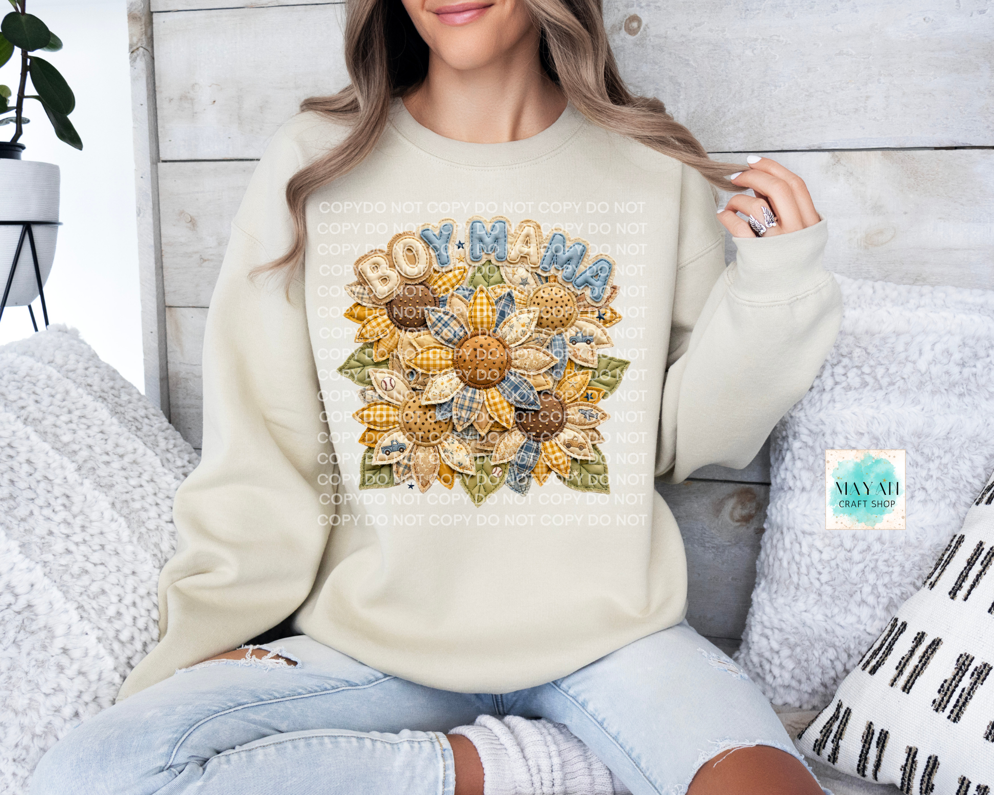 Person wearing a cream sweatshirt with a colorful 'BOY MAMA' design, sitting on a couch.