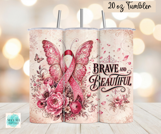 A 20 oz tumbler shown from the front with a wraparound design featuring a pink awareness ribbon, butterflies, roses, and the words “BRAVE AND BEAUTIFUL.” The tumbler has a light beige background with pink floral artwork and metal straws.
