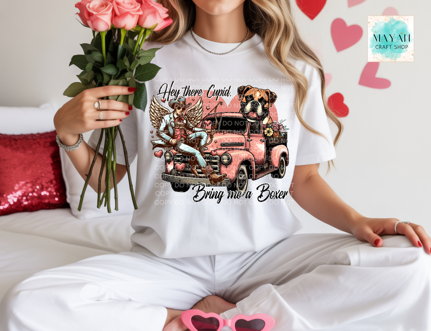 Person wearing a white t-shirt with a graphic design of a pink truck and text, holding flowers.