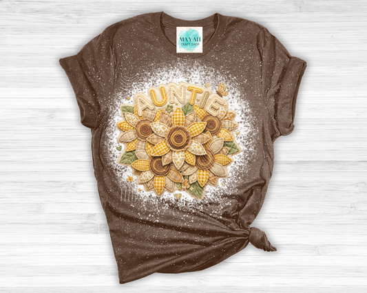 Brown t-shirt with a sunflower design and 'Auntie' text on a white wooden surface