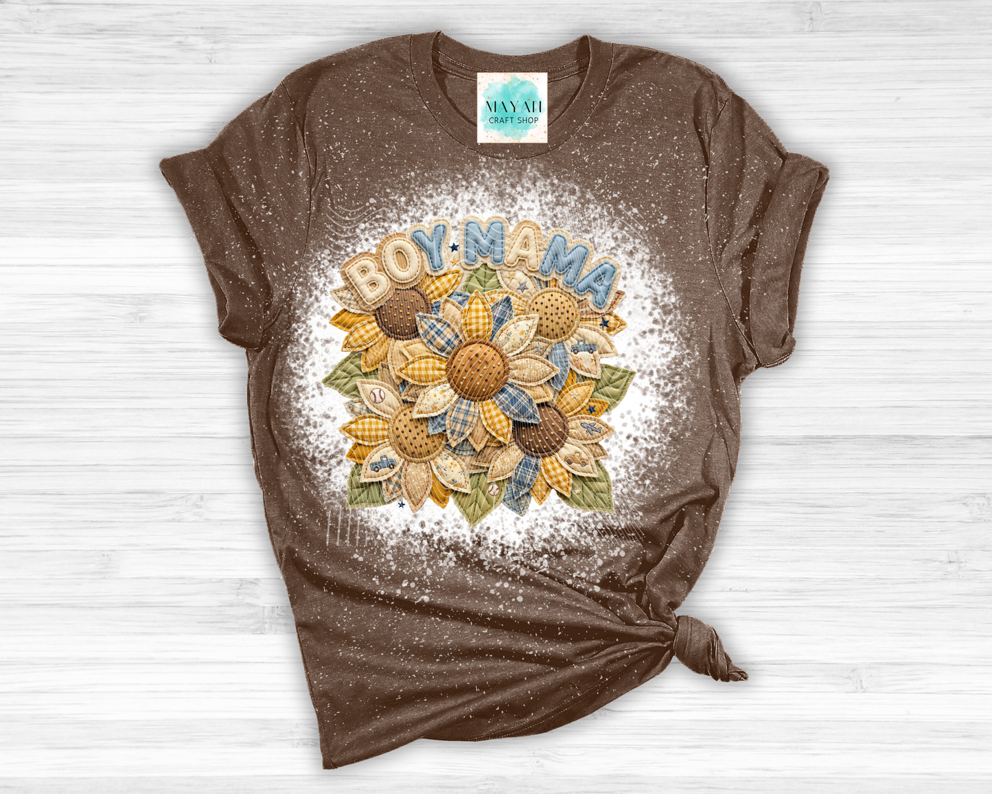 Brown t-shirt with sunflower design and 'BOY MAMA' text on a white wooden surface